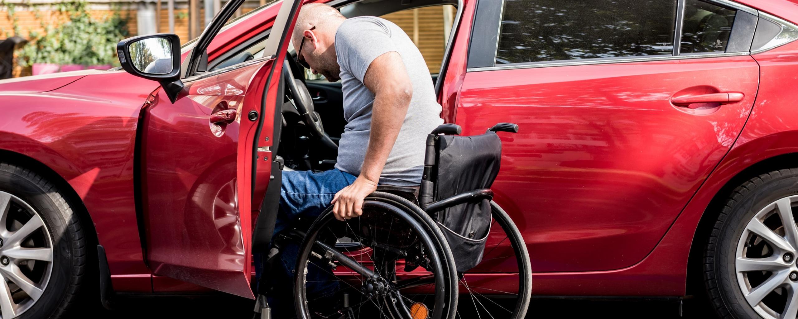 Man in rolstoel tilt zichzelf op bestuurdersplaats in een auto.